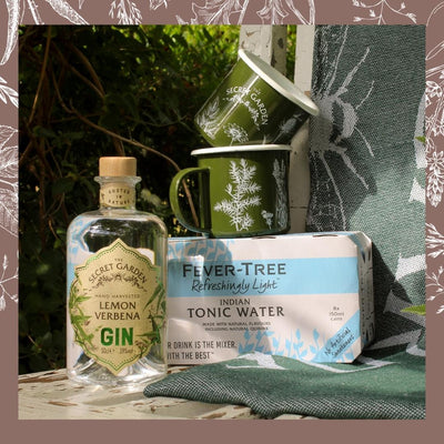 A picnic bundle featuring a 70cl bottle of premium gin, two enamel mugs, and a picnic blanket packaged in a wicker basket. Ideal for outdoor gatherings or as a gift for a loved one who enjoys gin and the great outdoors.