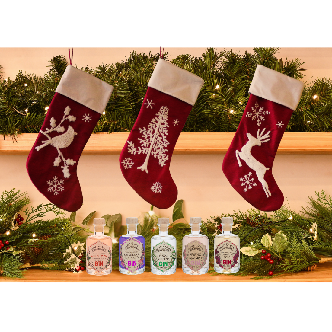 Three red Christmas stockings with white patterns hanging above a row of miniature luxury gin bottles on a decorated shelf.