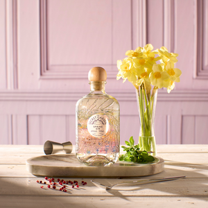 Handcrafted Scottish gin with natural spring botanicals from Secret Garden Distillery on a wooden board in a pink-panelled room